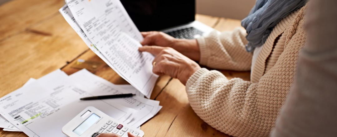 Beschnittene Ansicht einer älteren Frau, die von ihrer Tochter Hilfe bei ihren Finanzen erhält. Beschnittene Ansicht einer älteren Frau, die von ihrer Tochter Hilfe bei ihren Finanzen erhält.
