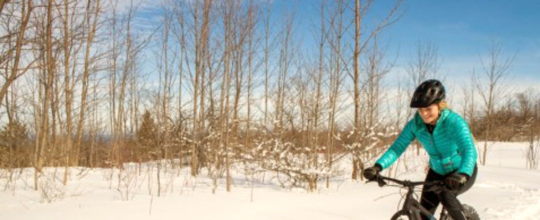 Eine junge Frau fährt mit einem Mountainbike durch die Schneelandschaft