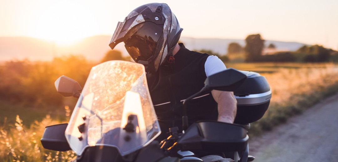 Motorradfahrer macht während einer Fahrt auf der Landstraße bei Sonnenuntergang eine Pause.