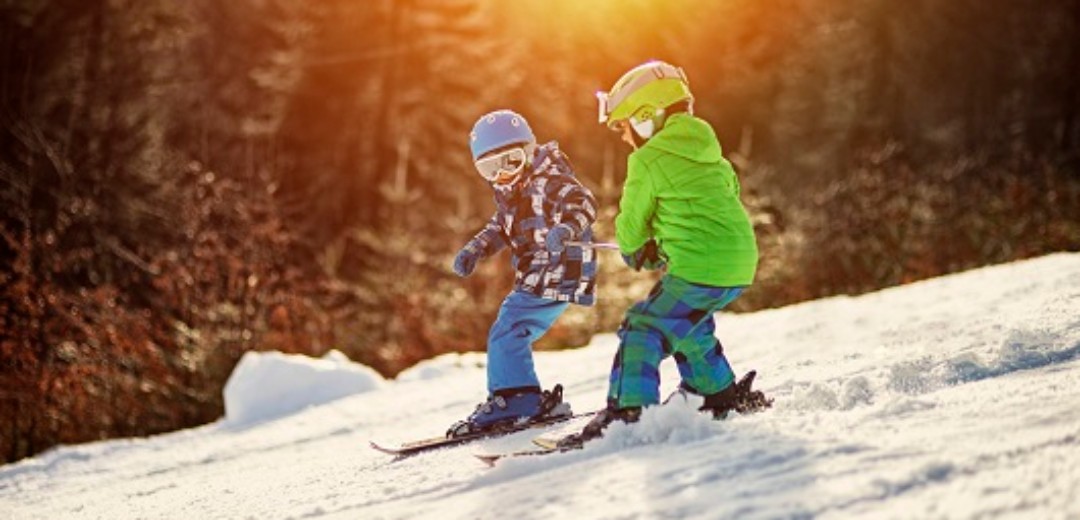 Zwei kleine Kinder mit ihren Skiern auf der Skipiste.