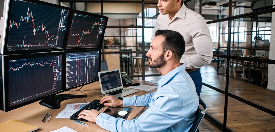 Zwei Männer sind im Büro und schauen zusammen auf einen Computerbildschirm.