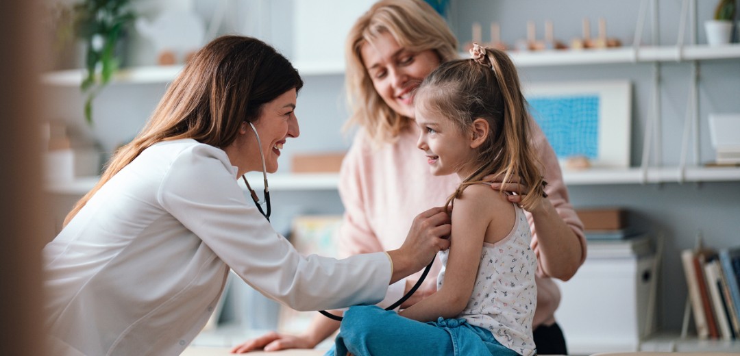 Eine Ärztin hört mit einem Stethoskop die Lunge eines kleinen Mädchens ab.