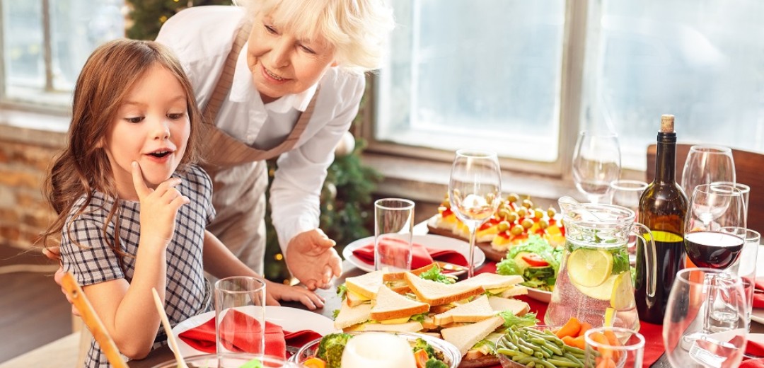 Eine ältere Dame und ein junges Mädchen stehen gemeinsam an einem Weihnachtsbuffet.