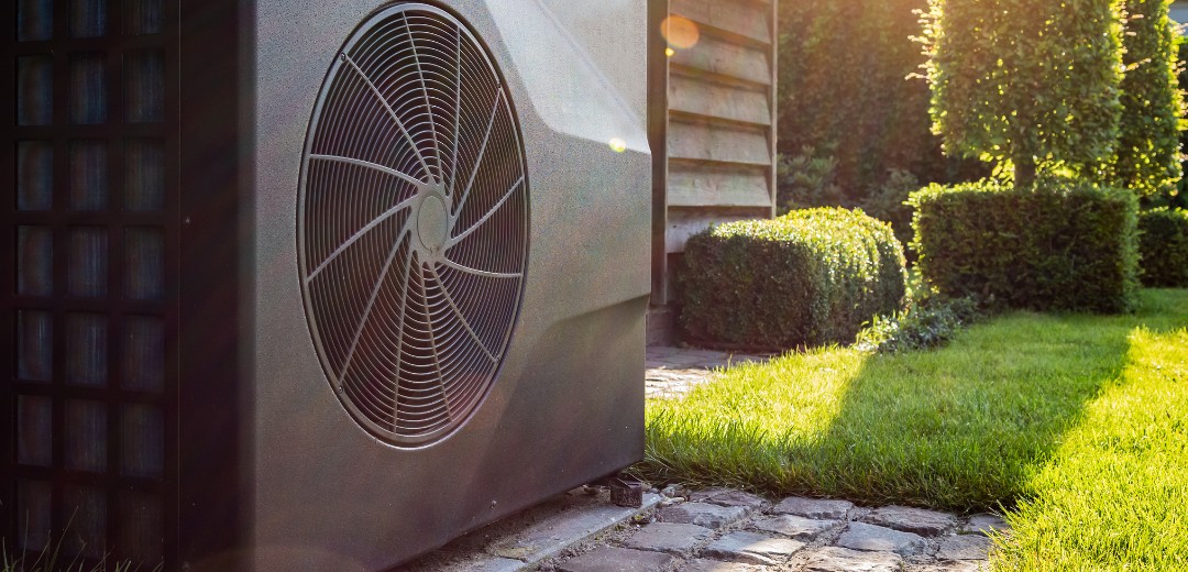 Eine im Garten stehende Wärmepumpe bei Sonnenlicht.