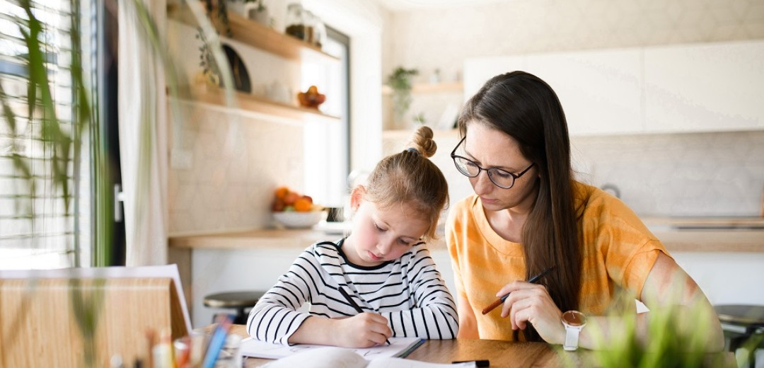 Eine Frau macht mit ihrer Tochter gemeinsam Schulaufgaben. 