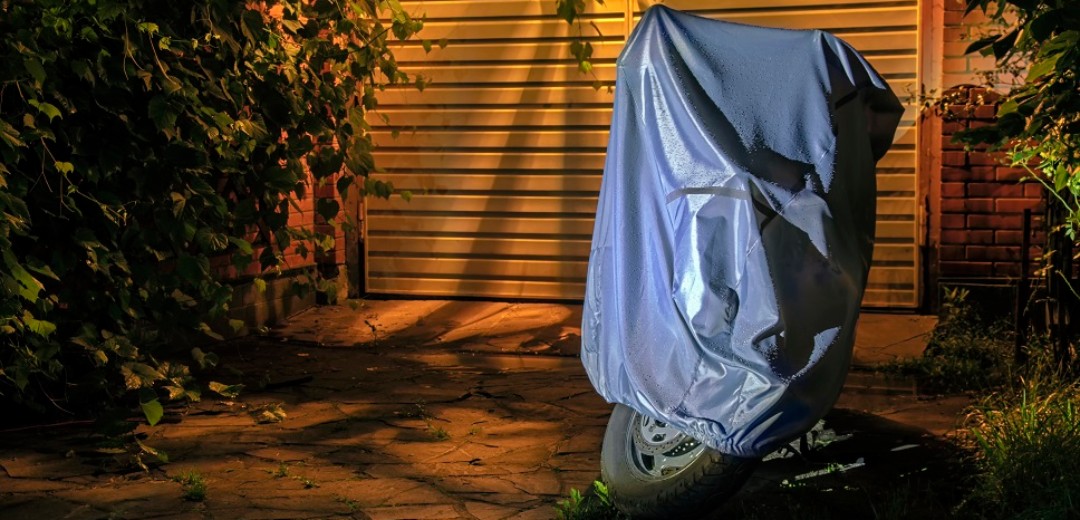 Ein überdecktes Motorrad steht im Dunkeln in der Auffahrt eines Hauses.