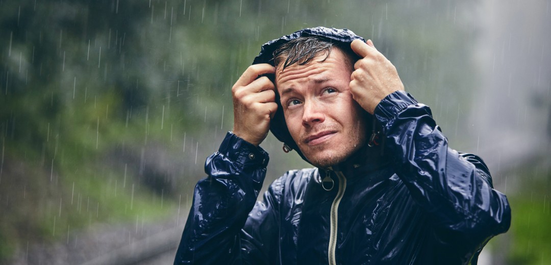 Ein Mann hat seine Kapuze auf, um sich vor dem starken Regen zu schützen.