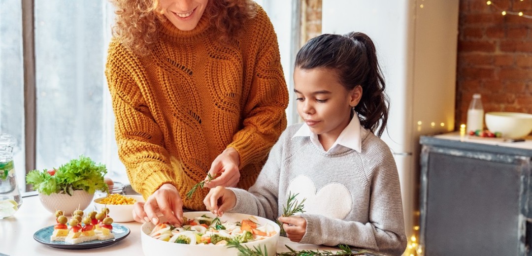 Eine Mutter macht  mit ihrer Tochter einen Auflauf in der Küche zusammen. 
