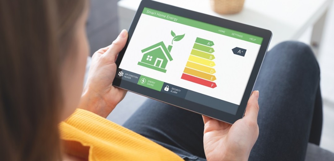 Eine Frau sitzt auf dem Sofa und schaut sich die Energieeffizienzklassen auf dem Tablet an.