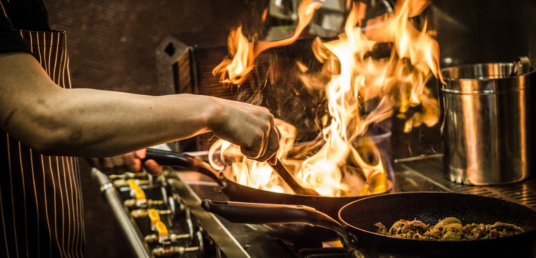 In einer professionellen Küche kocht ein Koch mit Feuer