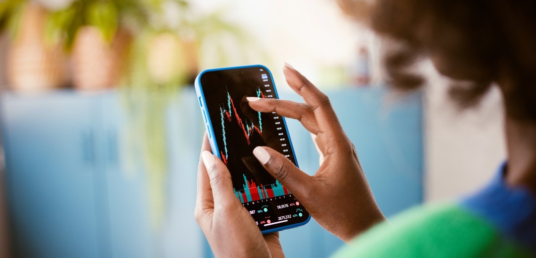 Frau zoomt mit den Fingern näher an eine Aktien-Grafik auf ihrem Handy.
