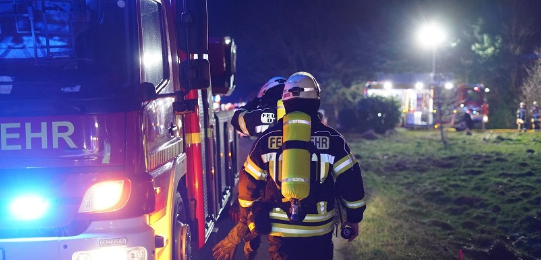 Feuerwehrmänner gehen entlang Feuerwehrauto zum Einsatz abends.