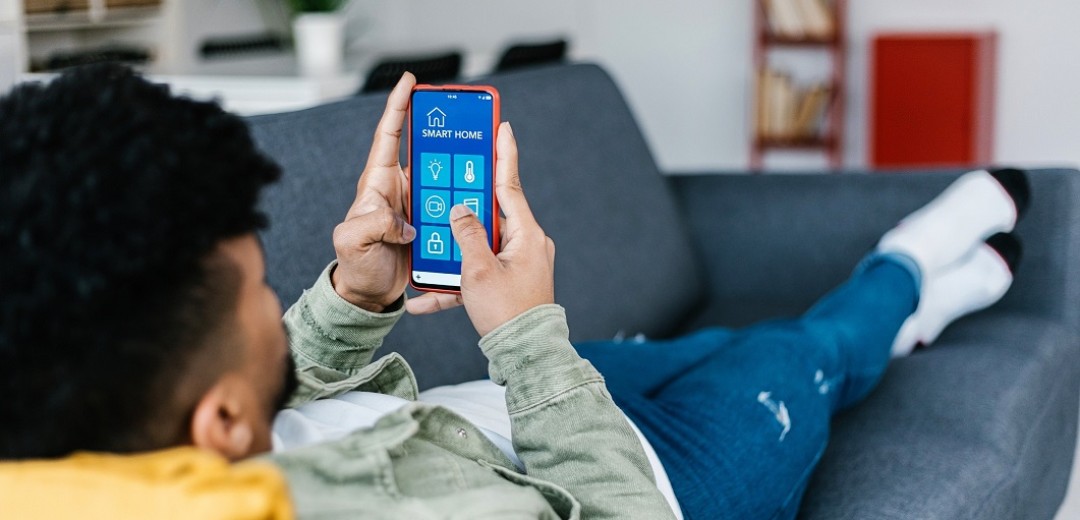 Ein Jugendlicher liegt auf dem Sofa und hält sein Mobiltelefon in der Hand. 