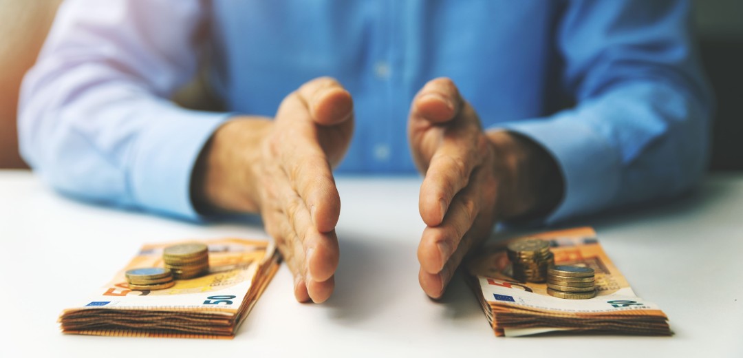 Ein Mann teilt Bargeld in zwei Stapel auf. 