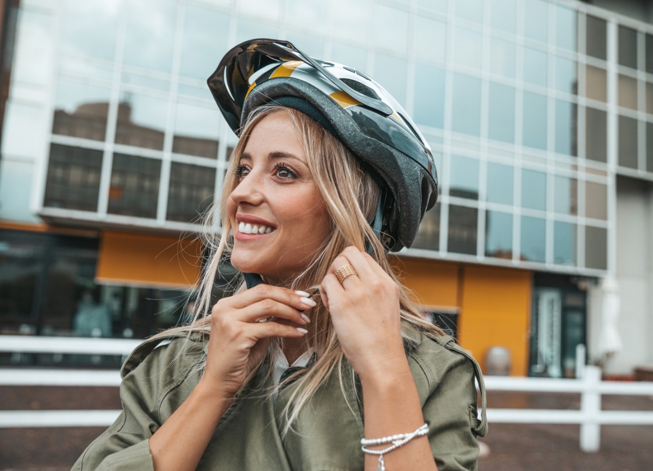 Eine Frau setzt sich einen Helm auf und lächelt dabei