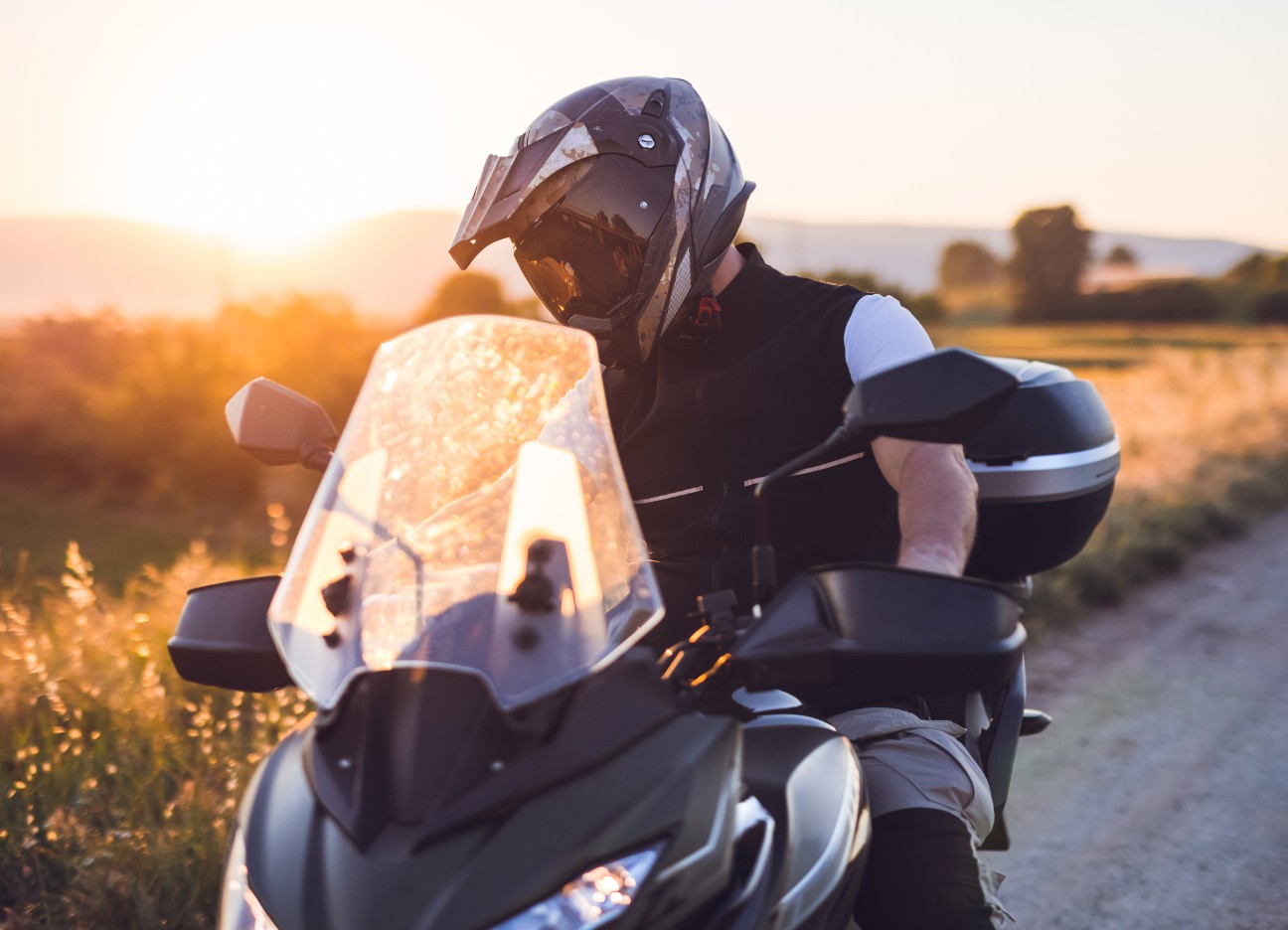 Motorradfahrer macht während einer Fahrt auf der Landstraße bei Sonnenuntergang eine Pause.