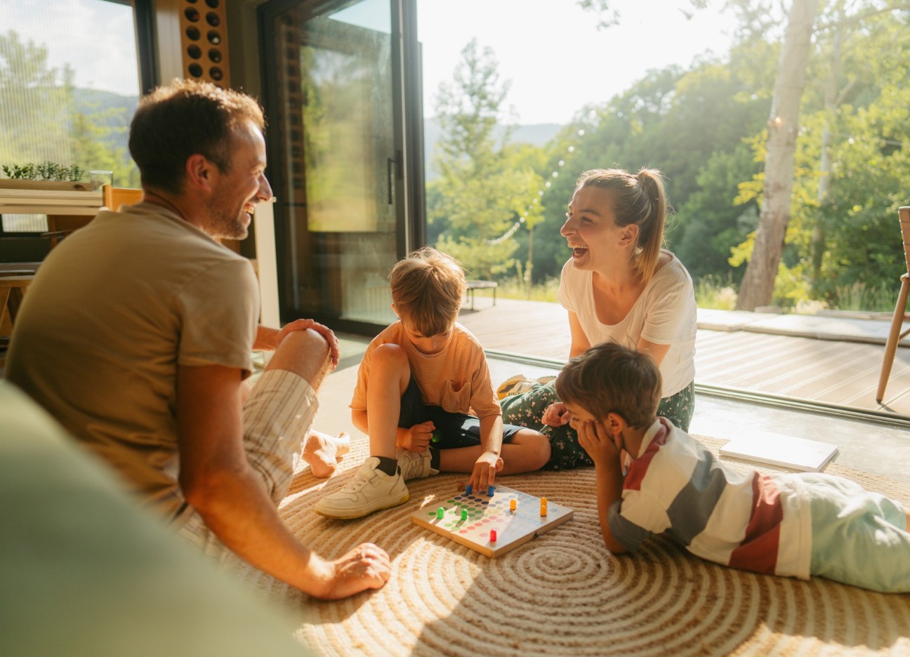 Junges Ehepaar spielt mit zwei kleinen Jungen im Wohnzimmer am Boden sitzend Mensch ärgere Dich nicht Junges Ehepaar spielt mit zwei kleinen Jungen im Wohnzimmer am Boden sitzend Mensch ärgere Dich nicht