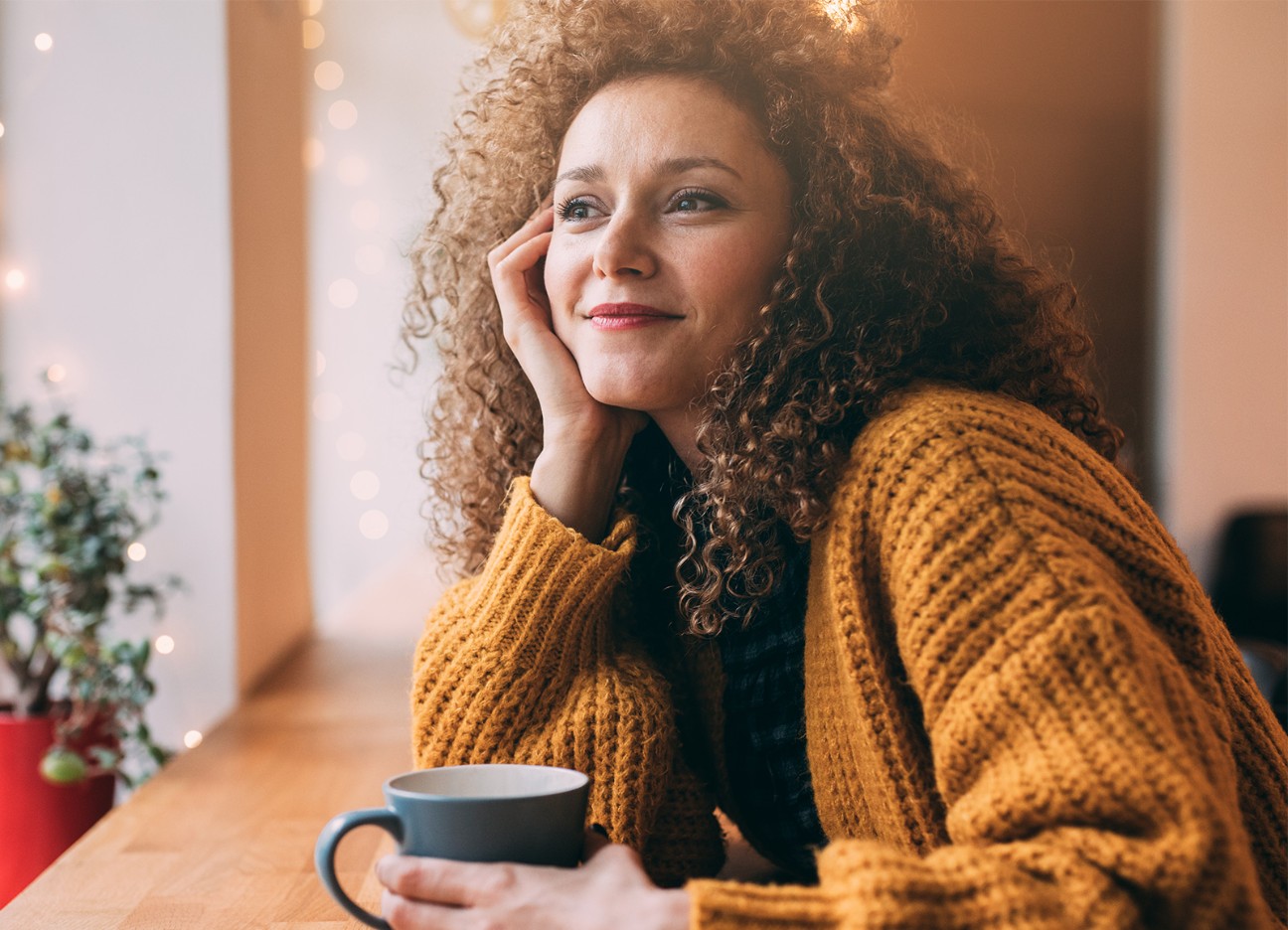 Junge Frau in Gedanken, hält Tasse in der Hand Junge Frau in Gedanken, hält Tasse in der Hand