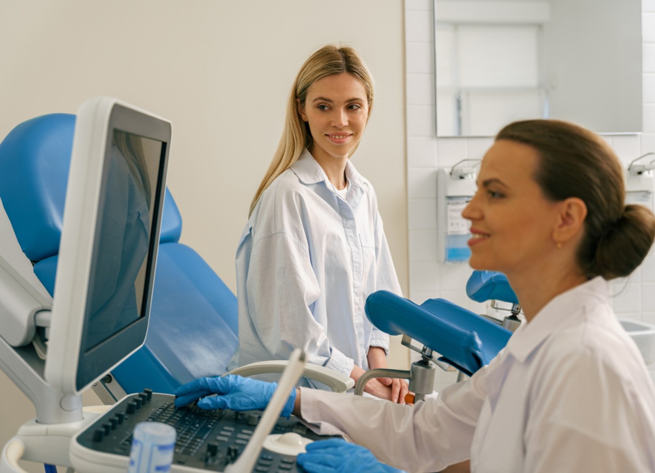 Patientin beim Gynäkologen, Ärztin bereitet eine Untersuchung im Behandlungsraum vor.