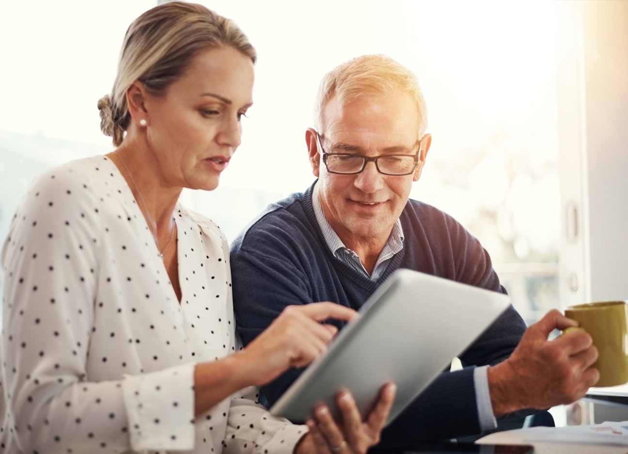 Bühnenbild Ratgeber Grundsteuerreform Ein Mann und eine Frau schauen gemeinsam auf ein Tablet und besprechen etwas.