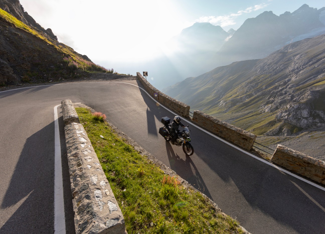 Motorradfahrer in einer scharfen Kurve vor einem Bergpanorama