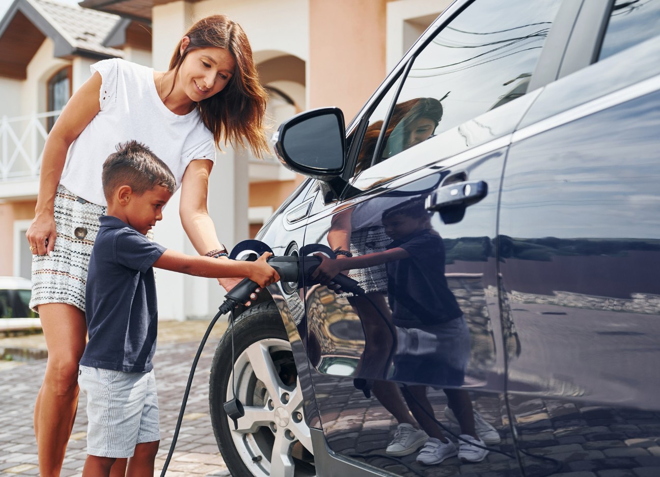 Eine Mutter und ihr kleiner Sohn schließen gemeinsam ihr Auto an die Ladesäule an