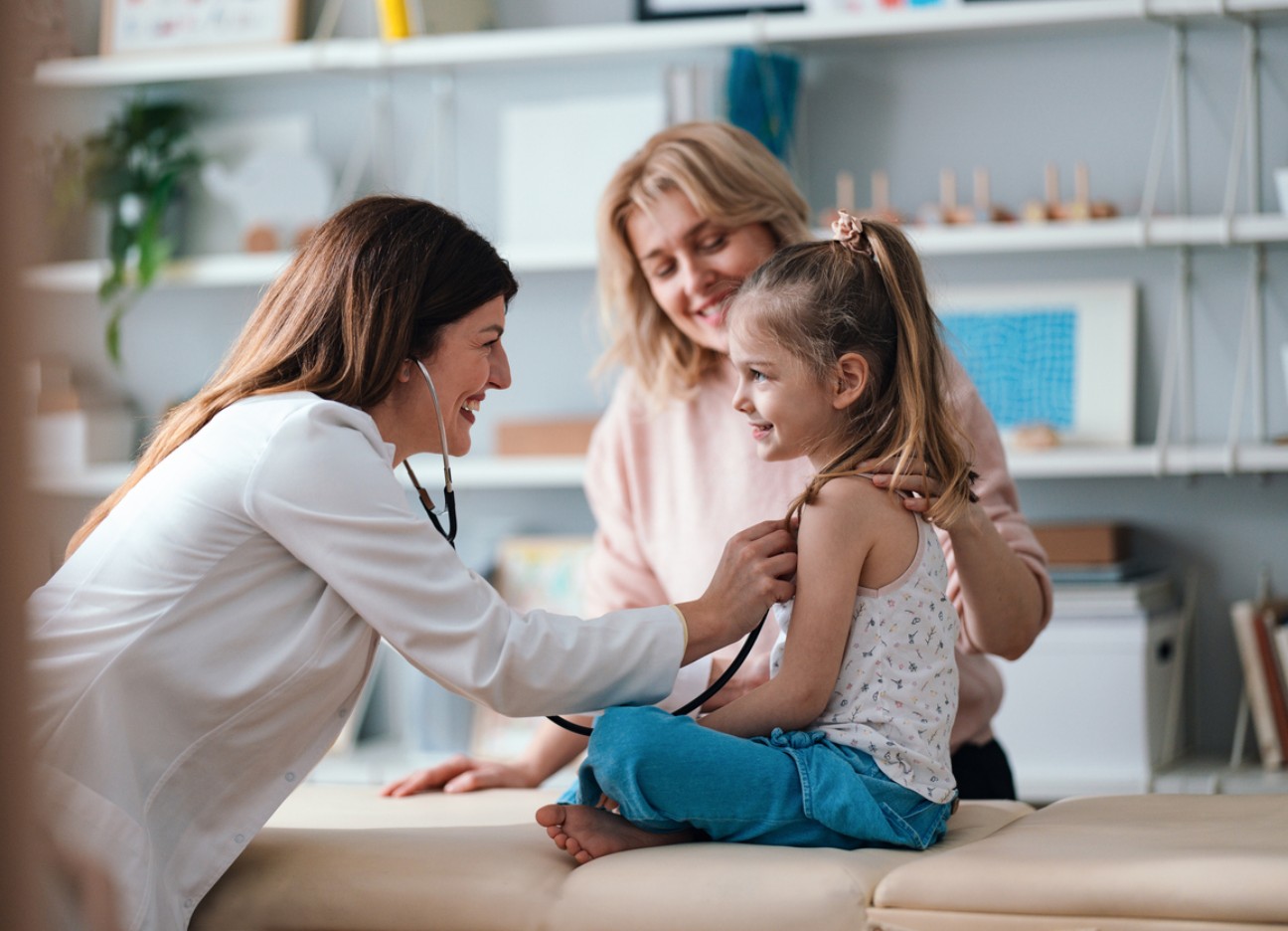Eine Ärztin hört mit einem Stethoskop die Lunge eines kleinen Mädchens ab.