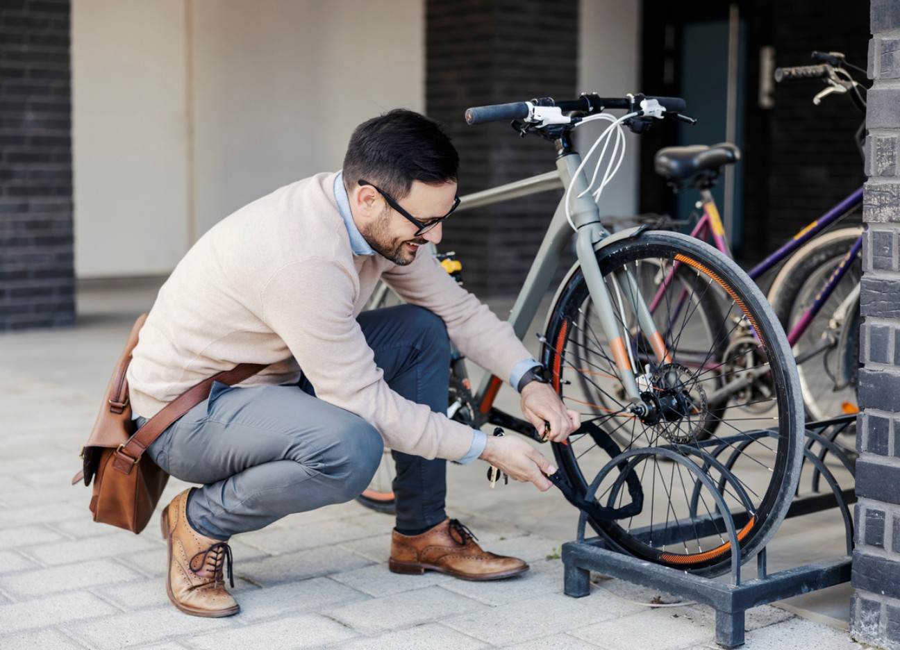 Ein Mann schließt sein Fahrrad auf der Straße ab.