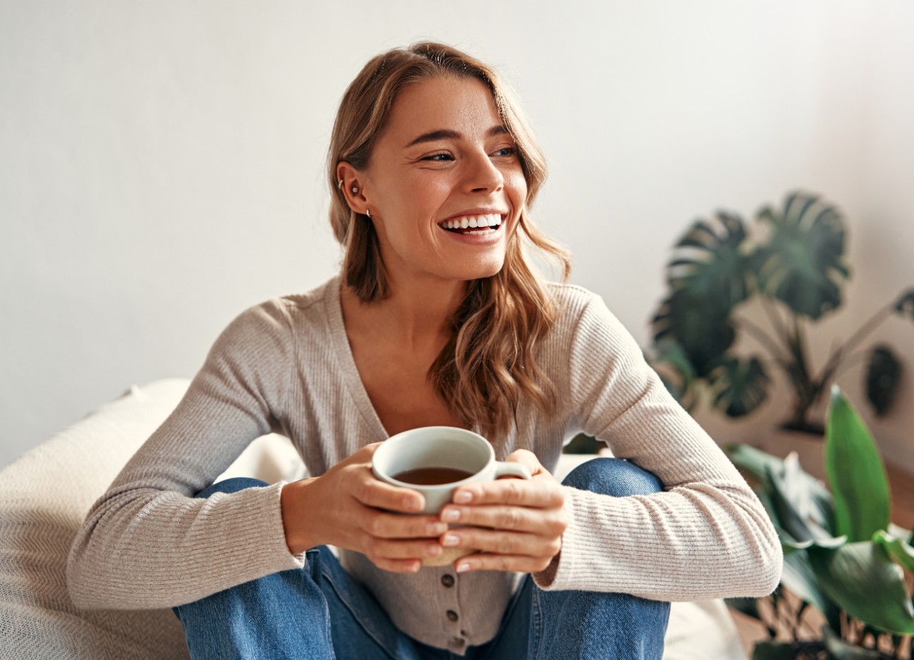 Eine Frau sitz lächelnd mit einer Tasse Kaffee auf dem Sofa. Eine Frau sitz lächelnd mit einer Tasse Kaffee auf dem Sofa.