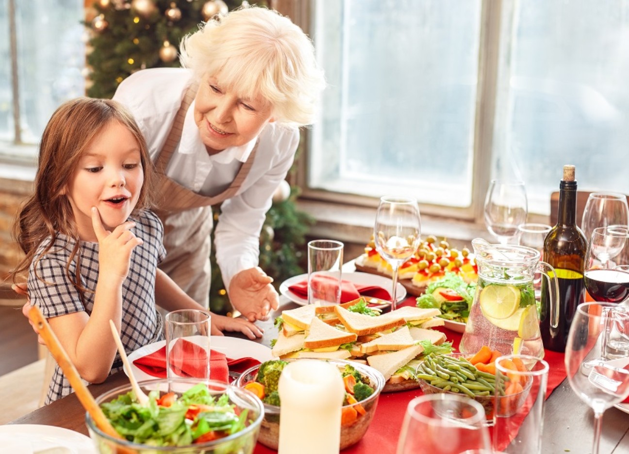 Eine ältere Dame und ein junges Mädchen stehen gemeinsam an einem Weihnachtsbuffet.