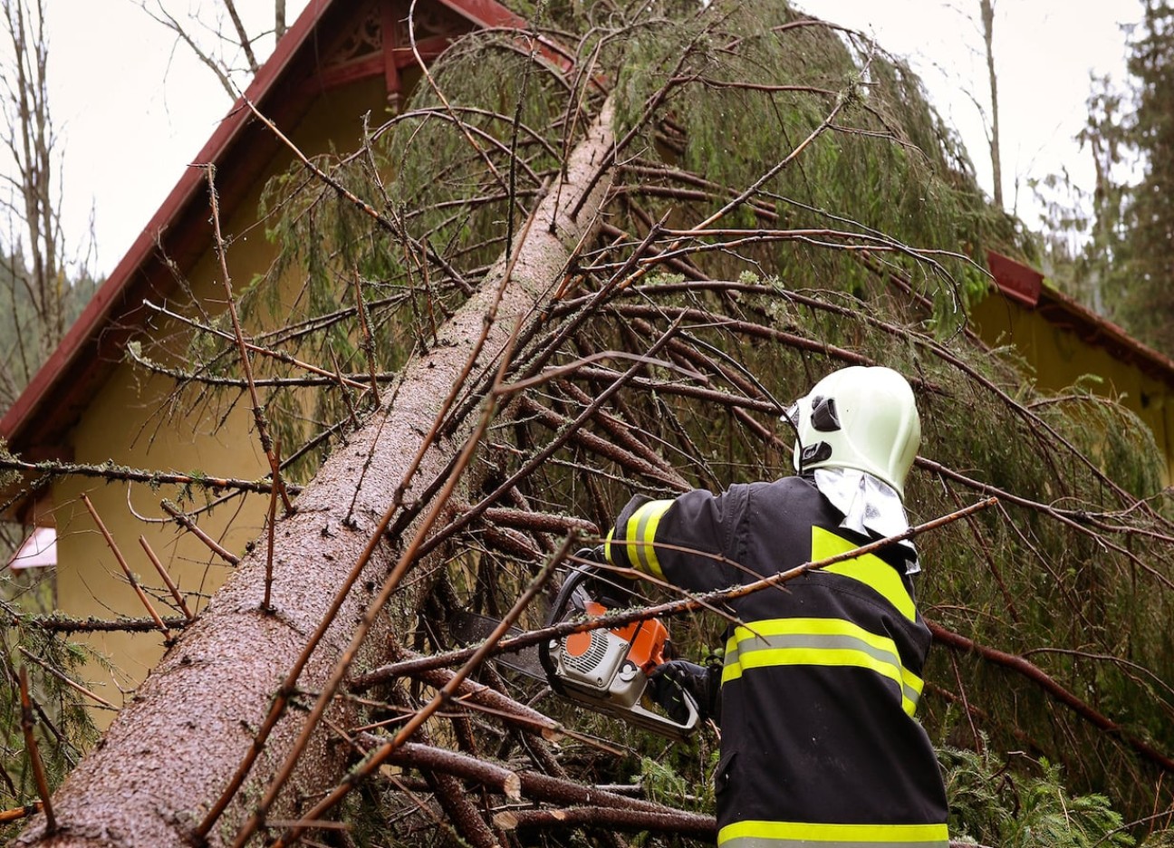 Feuerwehrmann zersägt umgestürzten Baum, der auf ein Haus gefallen ist. Feuerwehrmann zersägt umgestürzten Baum, der auf ein Haus gefallen ist.