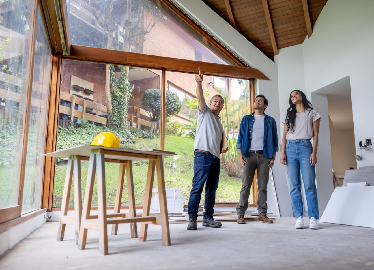 Bühnenbild: Ratgeber Barrierefrei Hausumbau Leitfaden Architekt zeigt einem Paar Details bei der Besichtigung eines Hauses mit großen Fenstern.
