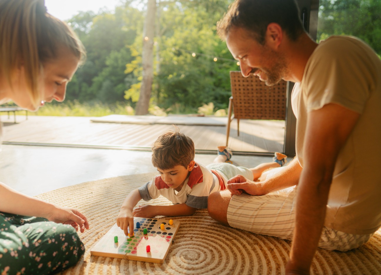Eine Familie sitzt auf dem Fußboden im Wohnzimmer und spielt ein Gesellschaftsspiel Eine Familie sitzt auf dem Fußboden im Wohnzimmer und spielt ein Gesellschaftsspiel