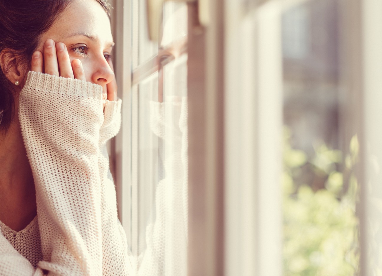 Bühnenbild Ratgeber Psychotherapie Eine junge Frau schaut aus einem Fenster in die Ferne.