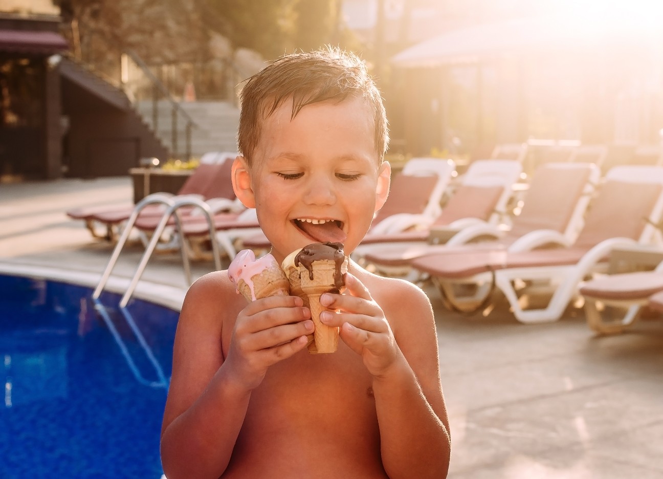 Bühnenbild Ratgeber Lebensmittelvergiftung verhindern Ein kleiner Junge isst drei Eis an einem Pool.