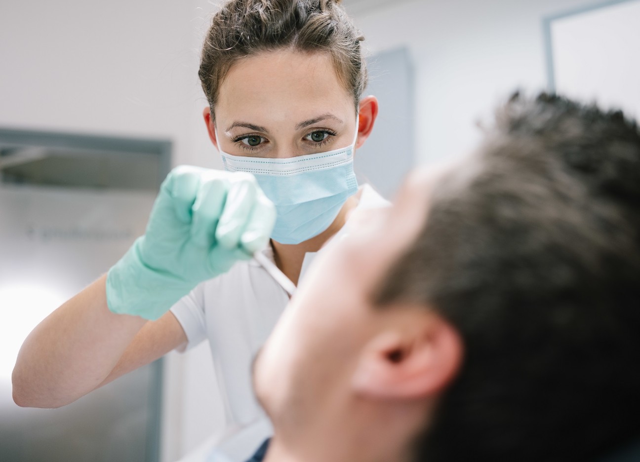 Eine Zahnärztin schaut einem Patienten in den Mund. 