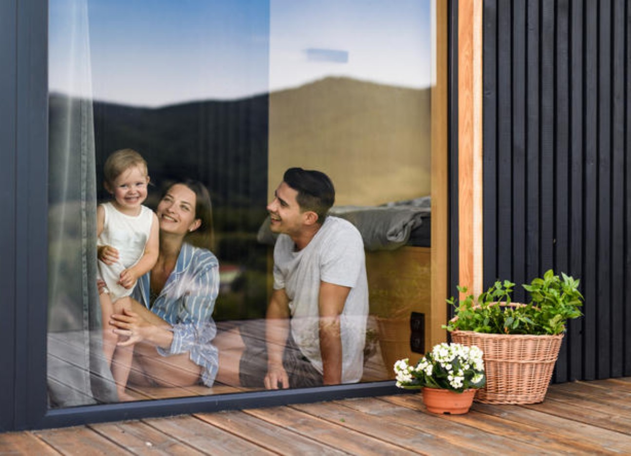 Eine Familie schaut lächelnd aus dem Fenster.