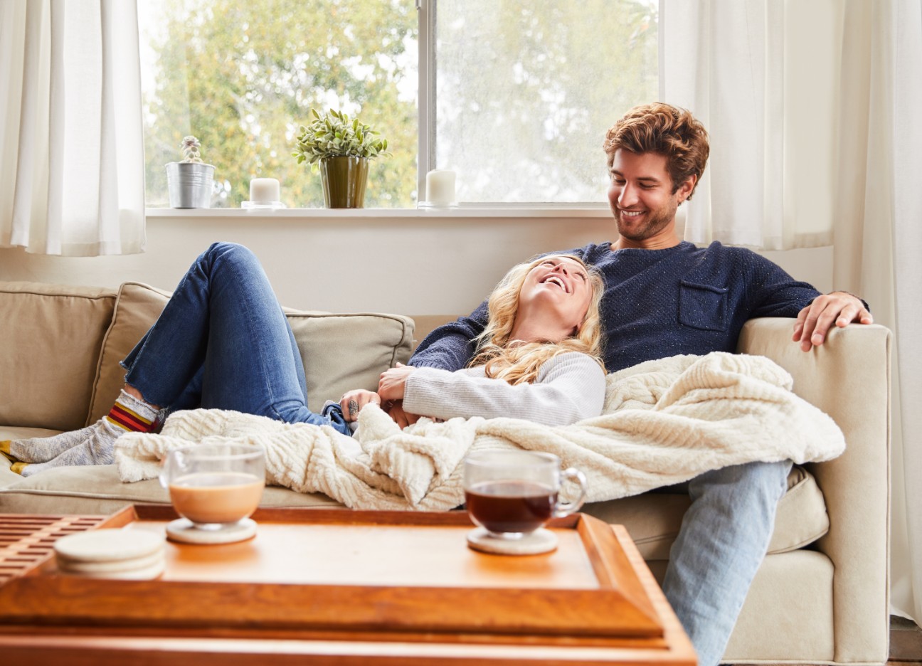 Ein Mann und eine Frau sitzen entspannt zuhause auf ihrem Sofa Ein Mann und eine Frau sitzen entspannt zuhause auf ihrem Sofa