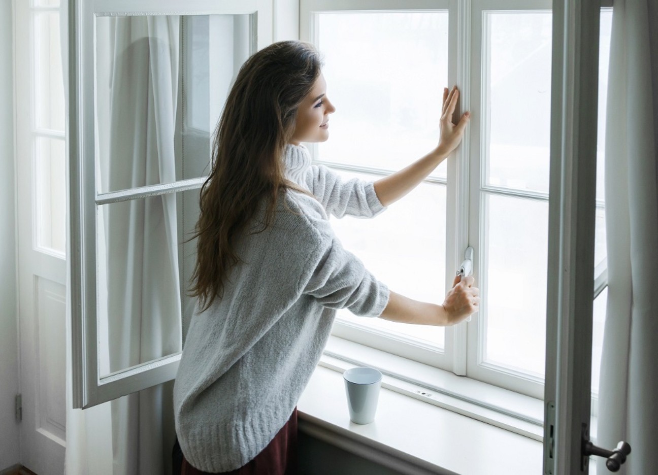 Bühnenbild Ratgeber Heizen Lüften Energiesparen Eine Frau schließt ein Fenster von Innen.