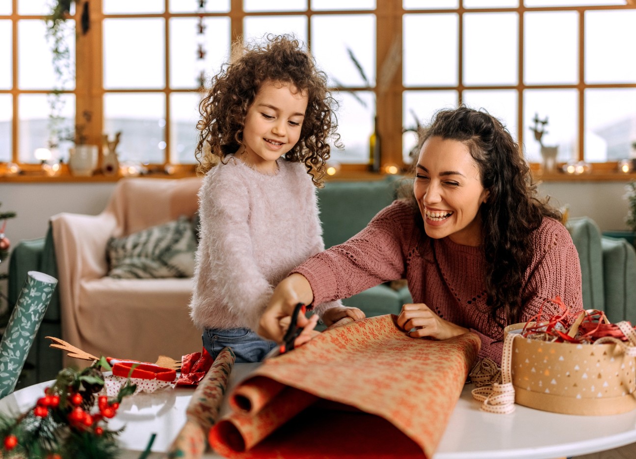 Bühnenbild Ratgeber Weihnachtschenkerei Eine Mutter packt mit ihrer kleinen Tochter Weihnachtsgeschenke ein.