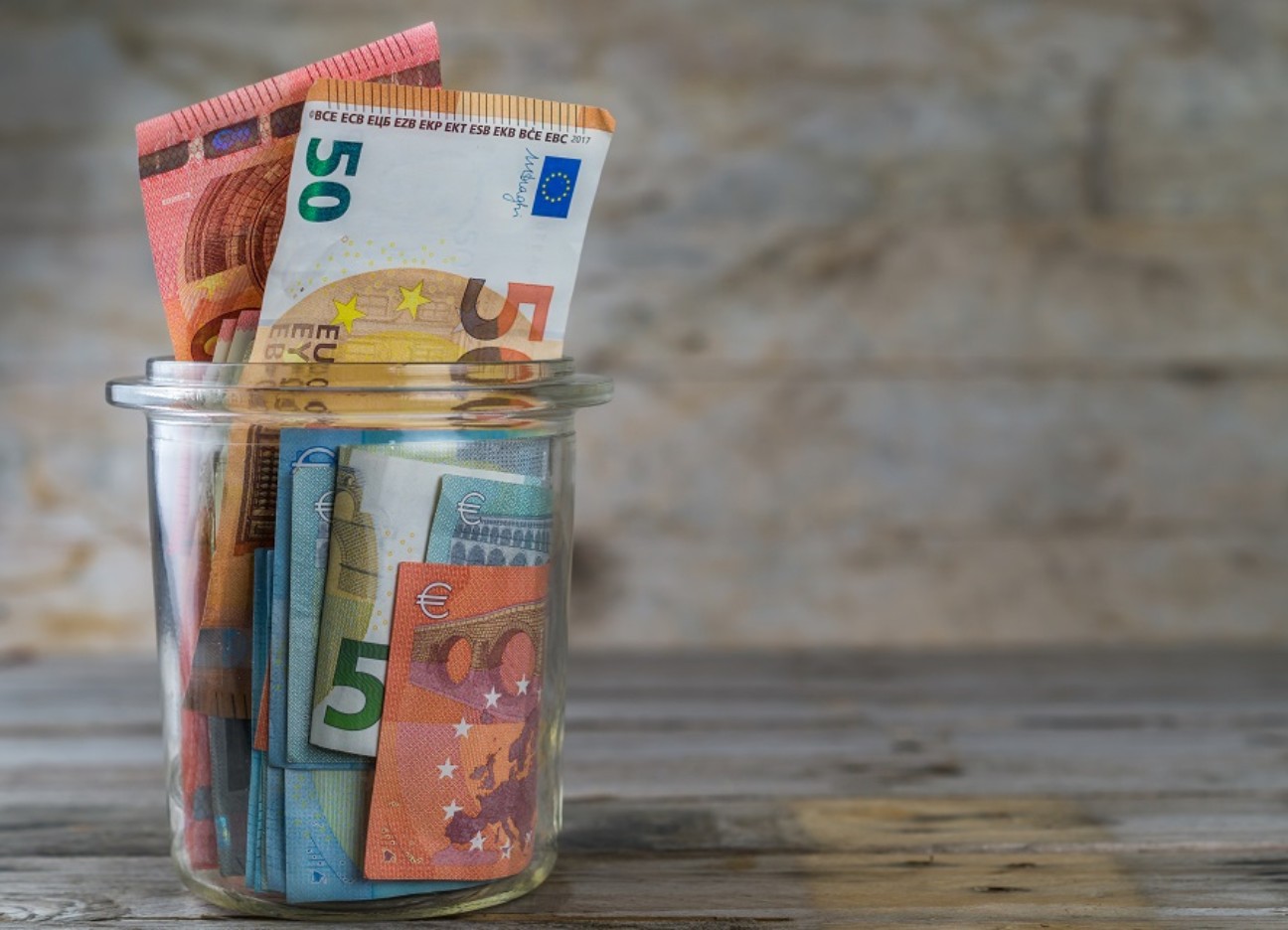 Bühnenbild Ratgeber Geldanlage bei Inflation Ein durchsichtiges Glas mit diversen Geldscheinen befüllt.