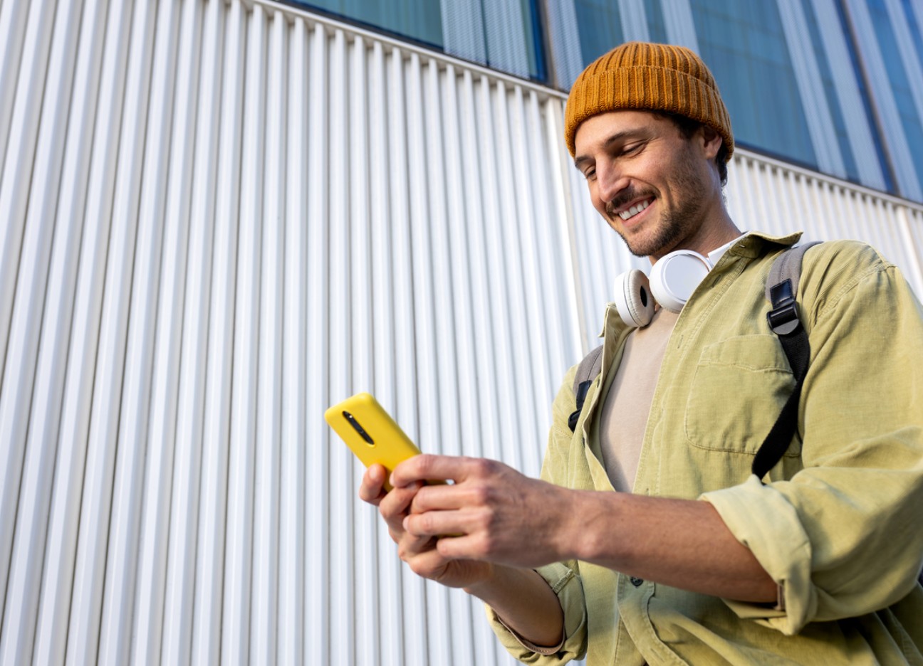 Ein junger Mann schaut beim Gehen lächelnd auf sein Handy