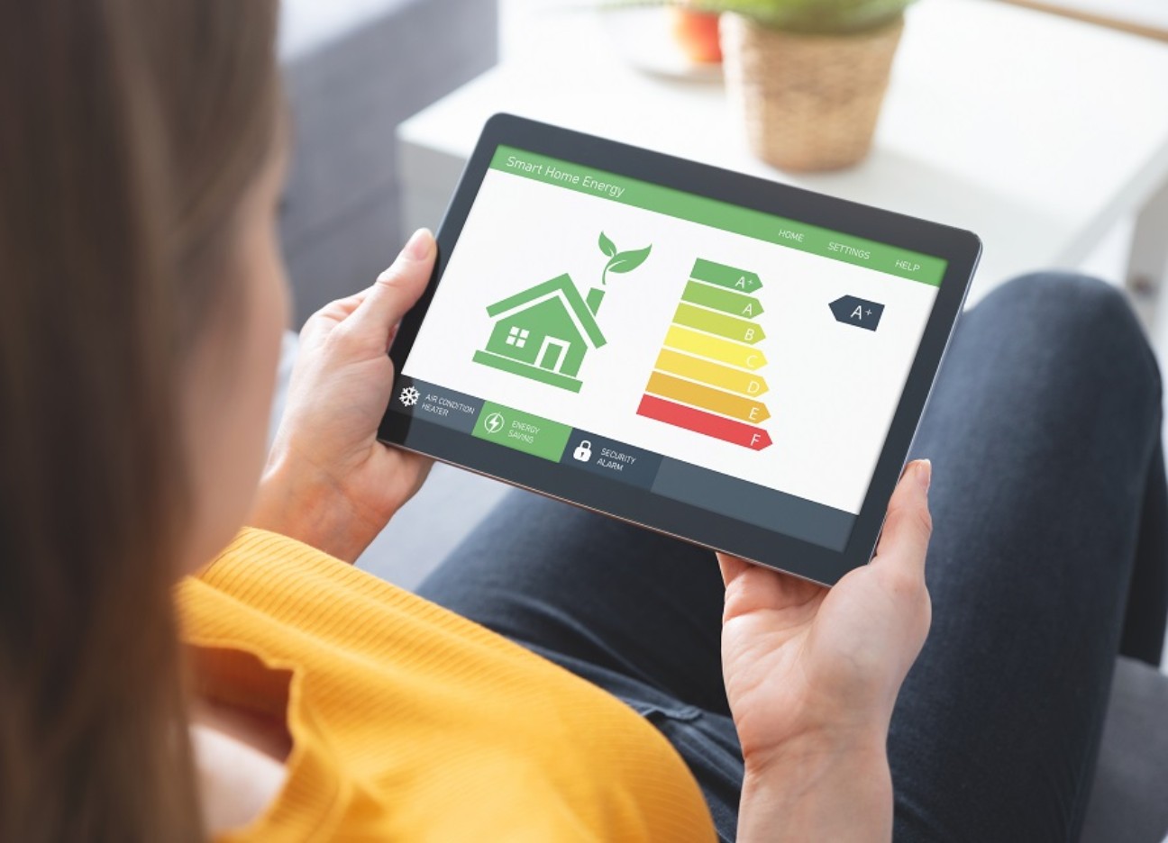 Eine Frau sitzt auf dem Sofa und schaut sich die Energieeffizienzklassen auf dem Tablet an.