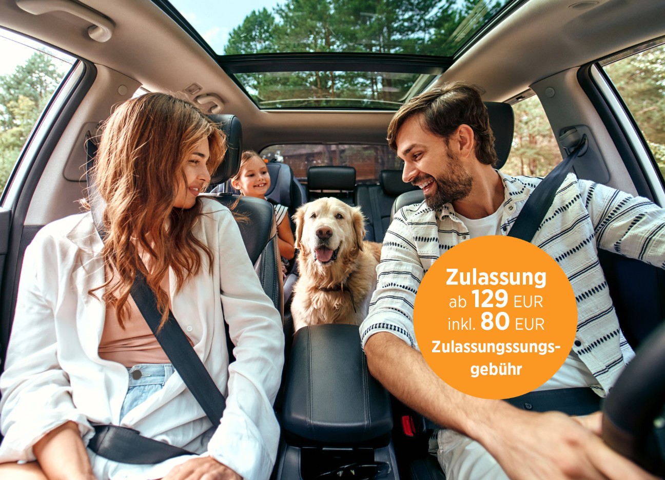 Eine junge Familie, fotografiert aus der Perspektive des Autocockpits, sitzt angeschnallt Auto und haben ihren goldbeigen Hund auf der Rückbank mit dabei.