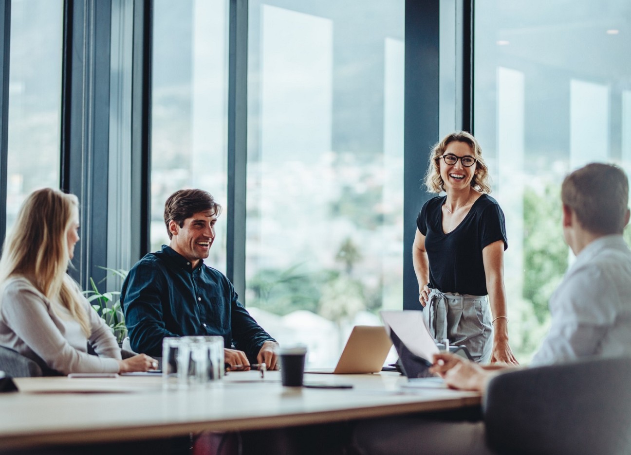Ein vierköpfiges Team diskutiert in einem hellem Büro mit großen Fenstern
