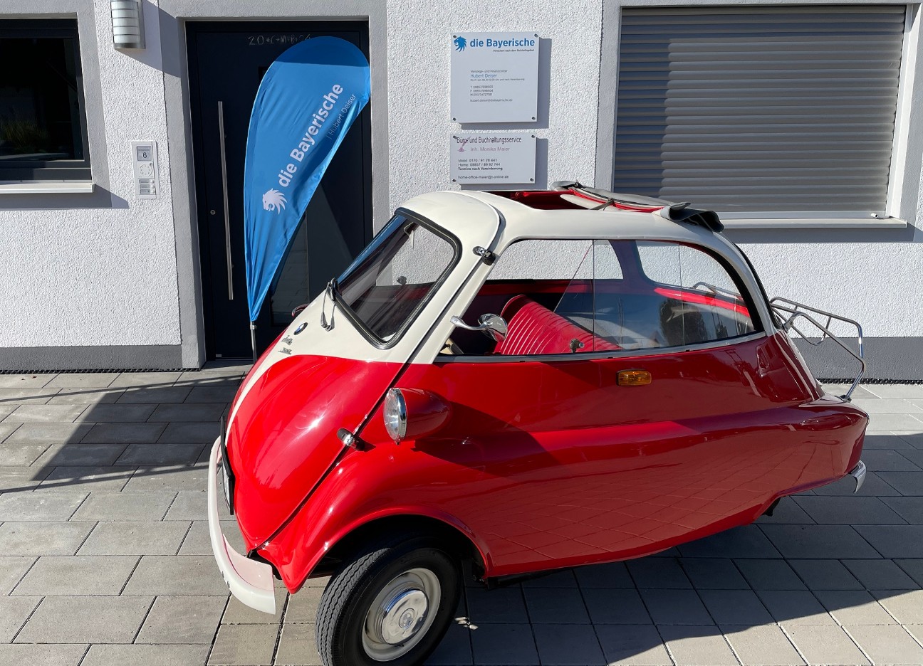 Roter Kabinenroller mit weißem Dach vor der Geschäftsstelle Hubert Deiser