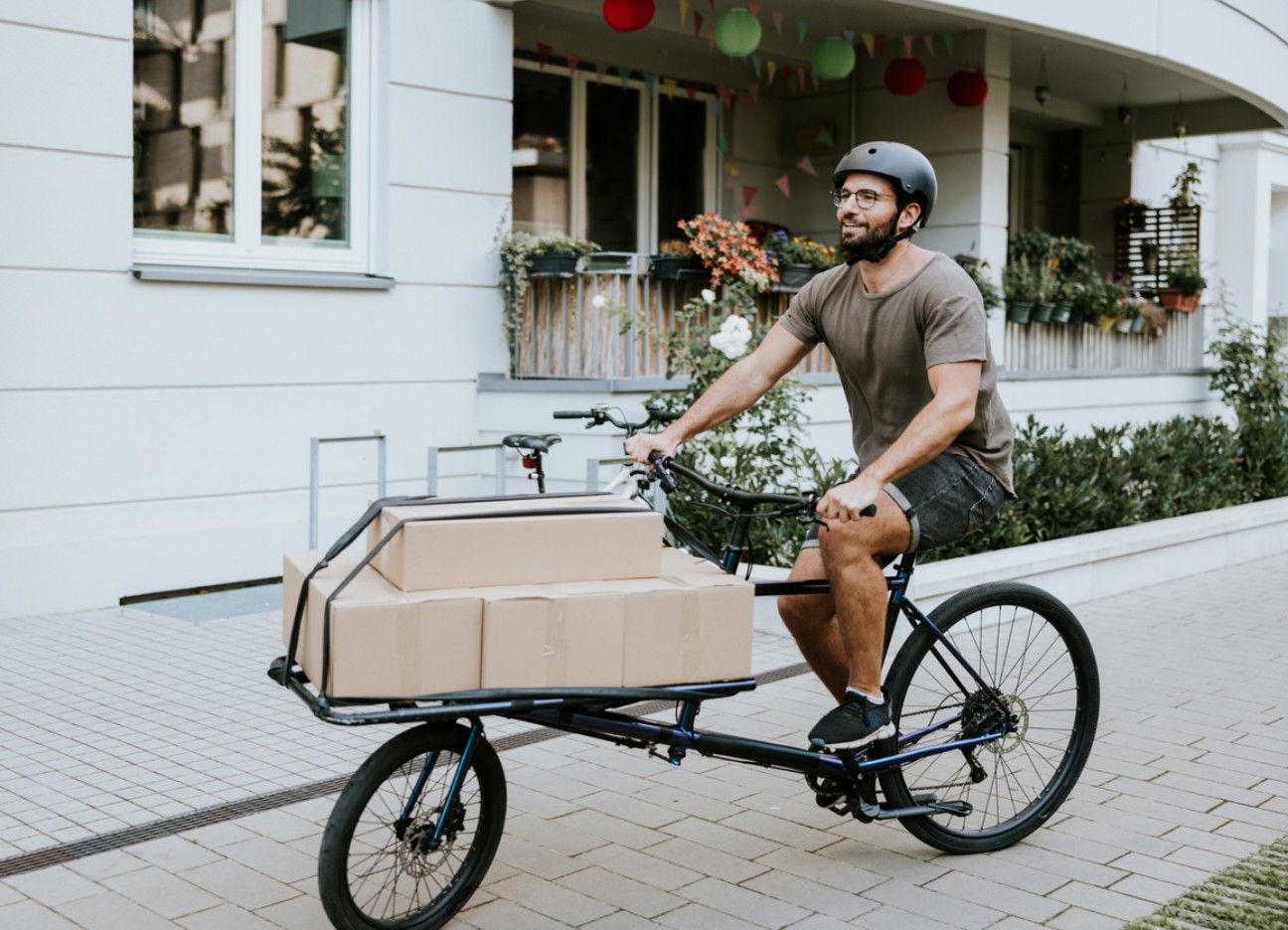 Ein junger Mann transportiert Kartons auf einem Lastenrad.