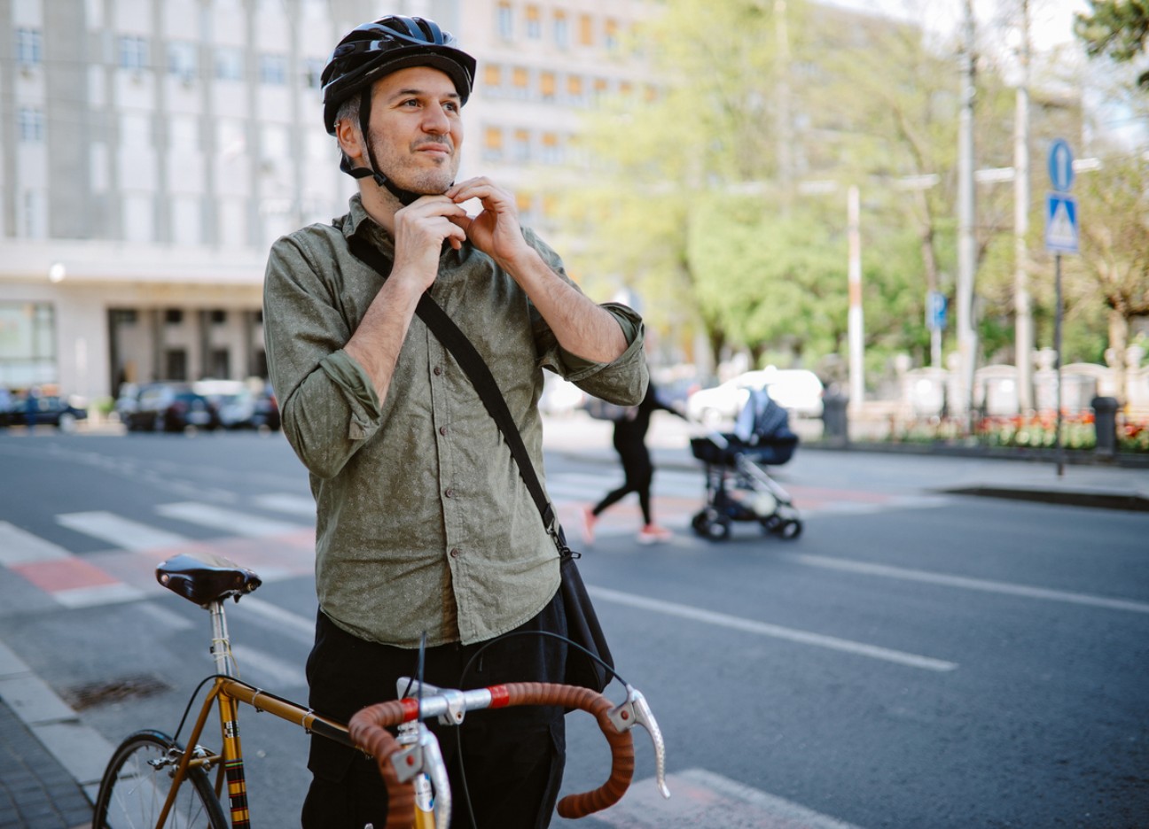 Urban cyclist adjusting a bicycle helmet before a city ride