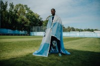 Spieler des TSV 1860 Leroy Kwadwo steht mit einer umgehängten Fahne auf dem Fußballplatz