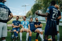 Mehrere Spieler des TSV 1860 sitzen auf einer Bank auf dem Spielfeld und andere stehen drumherum